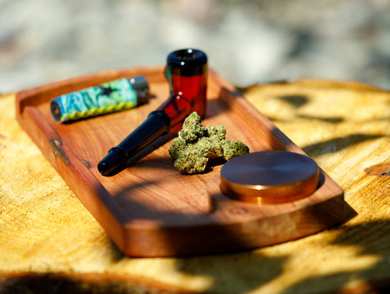A tray containing dried cannabis flower, a lighter, and a cannabis smoking pipe